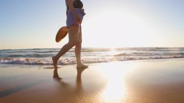 Altın gün batımında plajda yürüyen iri yarı bir kadının yan görüntüsü. Yaz tatilindeki kadın turist. Yaz havası. Sahildeki kız..