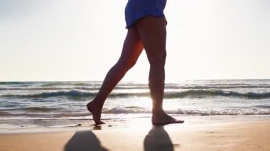 Gün batımında sahilde yürüyen mutlu ve boyunda bir kız. Yaz havası. Sahil ve tatil.