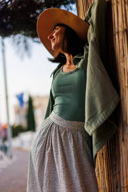 Şık yaz kıyafetleri içinde güzel bir esmerin portresi. Tatil sırasında sokakta gülümseyen neşeli genç bir kadın. Mutlu kız..