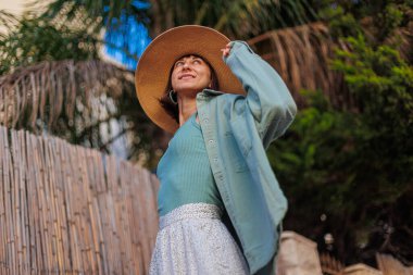 Şık yaz kıyafetleri içinde gezen güzel bir esmerin portresi. Yaz tatili boyunca sahilde gülümseyen neşeli genç bir kadın. Mutlu kız..