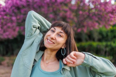 Genç kız şehirde mutlu bir şekilde duruyor. Şık yaz kıyafetleri içinde güzel bir esmerin portresi. Tatil sırasında sokakta gülümseyen neşeli genç bir kadın. Mutlu kız..