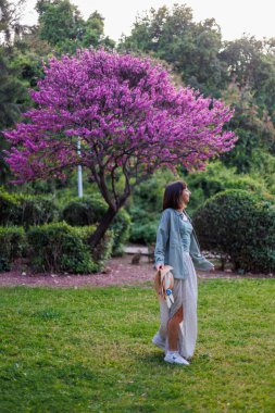 Mutlu bir kızın portresi. şehir tarzı ve moda. Genç bir esmer, şehir bahçesinde yürürken mutlu bir şekilde gülümser. Gömlekli, şık bir kız. Yaz Portresi