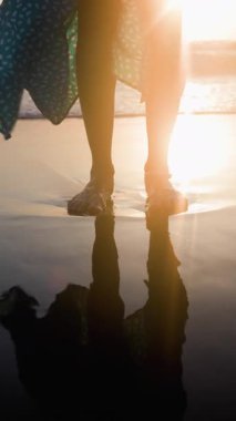 Dikey çekim. Genç ve zayıf kadın sahilde huzurlu bir gün batımının tadını çıkarırken hayat yolculuğunu yansıtıyor. Romantik