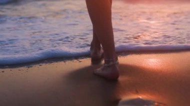 Genç ve zayıf bir kadın kumsalda yavaşça yürür ve denize girer. Plaj ortamında romantik bir atmosfer. Yaz havası