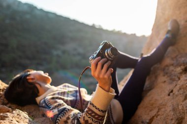 Dağlarda elinde kamerayla mutlu bir kadın. Dağlarda rahatlayan ve fotoğraf çeken bir kız. Yürüyüş ve yürüyüş. Kameralı kız. film kamerası.