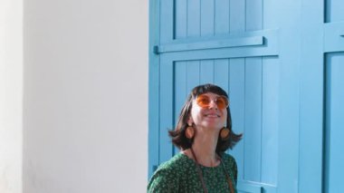 Çekici genç gezgin kadın güneş gözlüğü takıyor ve modern giyim tarzı fotoğraf çekiyor ve kameraya bakıyor.