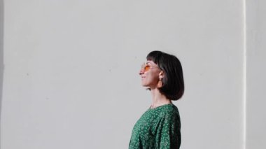 Şık görünümlü güzel bir kadın, şık güneş gözlükleriyle, kendine güvenerek caddede yürüyor. Neşe