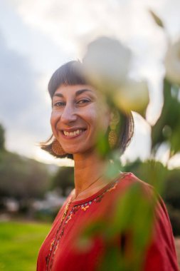 Romantik bir ruh hali. Güzel elbiseli güzel bir kadının portresi ve gün batımında elinde bir buket çiçekle. Kız gülümser ve kameraya bakar..