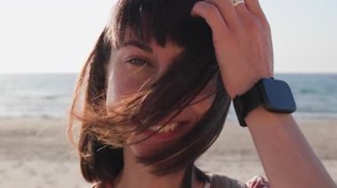 Yaz havası. Rüzgarlı bir günde kumsalda genç bir kız, yüzünde saçlar.