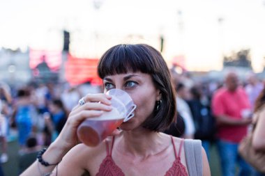 Kız müzik festivalinde eğleniyor ve bira içiyor. Bira içen ve müzik festivalinde eğlenen genç bir kadın. tatil kavramı.