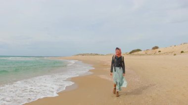 Deniz kıyısında yürüyen bir kadın kendini özgür hisseder. Romantik bir ruh hali. Doğada tatil ve eğlence..