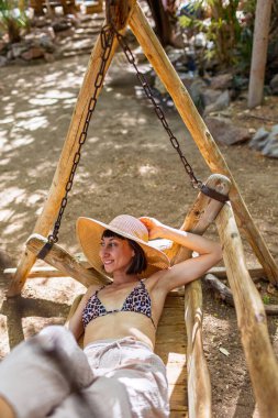 Plajın yakınındaki bir kafede sallanan bir kız, plajda güneşli sıcak bir gün. Tatildeki kız.