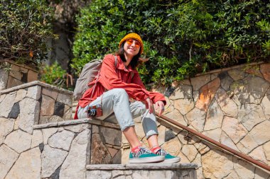 Şehirde bir turist. Şapkalı ve güneş gözlüklü şık bir kadının sokak portresi. şehirde seyahat etmek. Kız kameraya bakıyor..