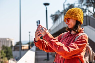 Kameralı mutlu kız şehirde dolaşıyor. Genç turist şehri geziyor ve geziyor. Şehirde dolaşan bir turist..
