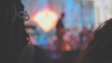 Bulanık ve bulanık. Konserde sahne ışıklandırması. Sanatçılar sahnede ışık ve duman içinde gösteri yaparlar. Seyirciler enerjik bir kayanın keyfini çıkarıyorlar