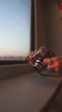 Dikey çekim. Trenle yolculuk. Fotoğrafçı kamerayı ayarlıyor. Elinde kamera olan genç bir kadın. Fotoğraf çeken bir turist
