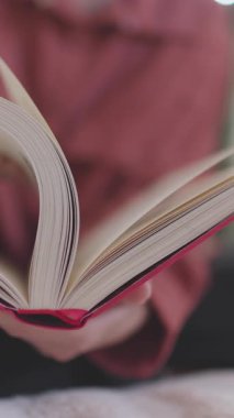 Dikey çekim. Elinde kitap olan bir kadın. Kız bilgi aramak için hızla kitabın sayfalarını çevirir. yakın plan