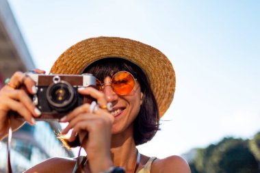 Kameralı kadın fotoğrafçı. Genç kız fotoğrafçı objektife nişan alıyor ve çekim sürecinden zevk alıyor. Kameralı şık bir kız. Seyahat ve tatil.