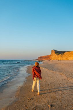 Mutlu neşeli kız sahilde eğleniyor. Sahilde kollarını sallayarak koşan çekici bir kadın. Gülümseyen neşeli bayan sahilde eğleniyor ve güzel doğanın tadını çıkarıyor..