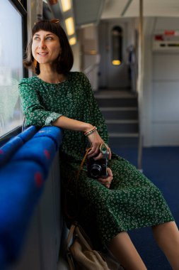 Tren yolcusu. Elinde kamera olan şık bir kız tren yolculuğunun tadını çıkarıyor. Tren yolculuğu. İyi yolculuklar..