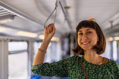 Kız toplu taşıma araçlarını kullanıyor. Trende duran kız. Her gün işe giderken toplu taşıma araçlarını kullanan mutlu ve çekici bir kadın..