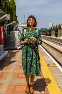 İstasyonun platformunda kameralı ve sırt çantalı genç ve güzel bir kız. İyi yolculuklar..