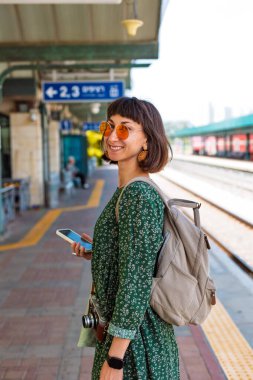 İstasyonun platformunda kameralı ve sırt çantalı genç ve güzel bir kız. İyi yolculuklar..