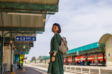 İstasyonun peronunda kameralı ve sırt çantalı genç ve güzel bir kız var ve tren saatine bakıyor. İyi yolculuklar..