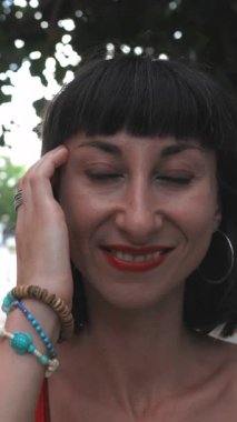 Dikey çekim. Gülümseyen kız saçını dışarıda düzeltiyor. Mutlu kadın yüz yüze. Yaşam tarzı kavramı.