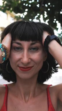 Dikey çekim. Gülümseyen kız saçını dışarıda düzeltiyor. Mutlu kadın yüz yüze. Yaşam tarzı kavramı.