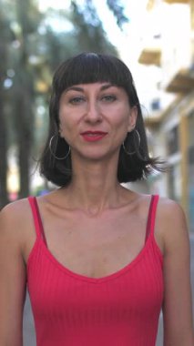 Dikey çekim, kırmızı gece elbisesi giymiş seksi esmer şehir caddesinde duruyor. Elbiseli kız.