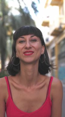 Dikey çekim, öpücük yollayan bir kız. Kırmızı elbiseli seksi esmer kameraya gülümsüyor ve neşeli bir öpücük gönderiyor. Bir kız...