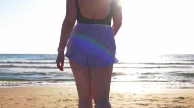 Sahilde yürüyen bir kız. Ayrıca plajda günbatımının tadını çıkaran bir manken. Yaz havası..