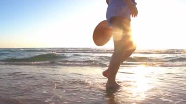Gün batımında sahilde yürüyen bir kız. Ayrıca plajda ıslak kumda yürüyen ve vücudunun tadını çıkaran bir manken.