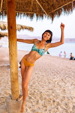 Sahilde ince bir kız. Tasasız genç kız okyanusa gülümsüyor. Eilat. İsrail. Seyahat ve tatil.