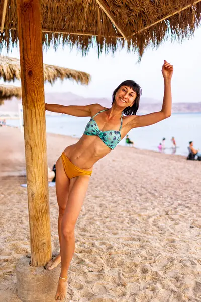 Sahilde ince bir kız. Tasasız genç kız okyanusa gülümsüyor. Eilat. İsrail. Seyahat ve tatil.