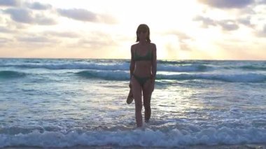 İnce kız denizde eğleniyor ve bacakları okyanus dalgalarıyla yıkanıyor. Sahildeki genç kız. Yaz havası.