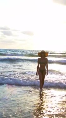 Dikey çekim. İnce kız denizde eğleniyor ve bacakları okyanus dalgalarıyla yıkanıyor. Sahildeki genç kız. Yaz havası.