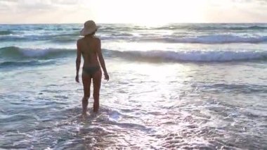 İnce kız denizde eğleniyor ve bacakları okyanus dalgalarıyla yıkanıyor. Sahildeki genç kız. Yaz havası.