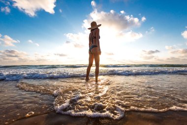 İnce kız denizde eğleniyor ve bacakları okyanus dalgalarıyla yıkanıyor. Sahildeki genç kız. Yaz havası.