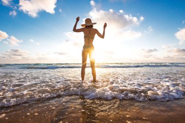 İnce kız denizde eğleniyor ve bacakları okyanus dalgalarıyla yıkanıyor. Sahildeki genç kız. Yaz havası.
