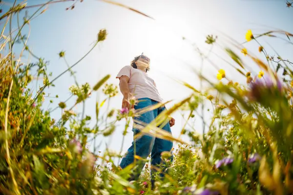 Genç ve neşeli adam çiçekler arasında dans ediyor. Doğada dans eden yakışıklı adam. Yaz havası. Çiçeklerin arasında mutlu bir genç adam, açık havada. bahar modası.