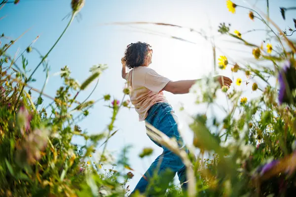 Yaz havası. Mavi gökyüzü ve çiçeklerin arka planında poz veren şık giyinmiş genç bir adam. bahar modası.