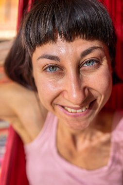 Tatilde hamakta dinlenen sakin bir genç kadın. Kız rahat bir şekilde dışarıda hamakta sallanıyor, stressiz bir hayat sürüyor. Yaz havası.