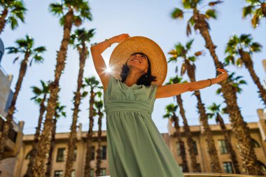 Neşeli gülümseyen stil sahibi bayan turist. Eski Jaffa şehrinde güzel caddelerde yürüyen elbiseli genç bir kadın. İsrail. Seyahat ve macera.