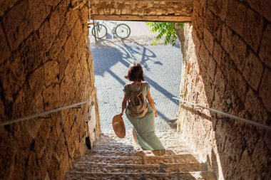 Kız tatilden ve şehirde gezmekten zevk alıyor. Eski Jaffa şehrinde güzel caddelerde yürüyen elbiseli genç bir kadın. İsrail. seyahat ve macera.
