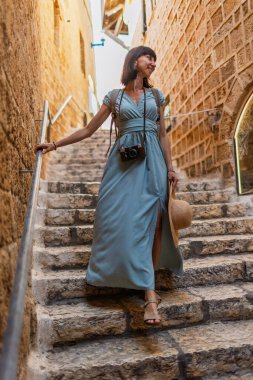 Açık havada yürüyorum. Neşeli gülümseyen stil sahibi kadın turist. Eski şehrin sokaklarında yürüyen bir gezgin. Seyahat ve tatil.