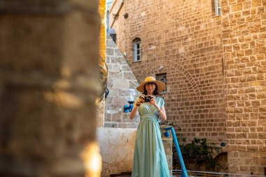 Kameralı kadın fotoğrafçı dışarıda fotoğraf çekiyor. Dışarıdaki kameralı kız. Gezintiler ve şehir yürüyüşleri. Yaşam tarzı, seyahat ve insan kavramı.