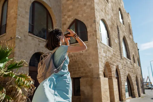 Şehirde fotoğraf çeken bir kadın fotoğrafçı. Genç bayan fotoğrafçı objektife nişan alıyor ve çekim sürecinin tadını çıkarıyor. seyahat ve içerik yaratmak. seyahat ve tatil.