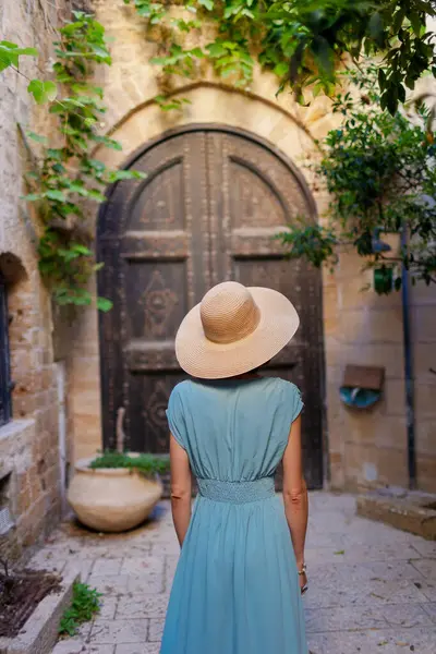 Kız tatilden ve şehirde gezmekten zevk alıyor. Eski Jaffa şehrinde güzel caddelerde yürüyen elbiseli genç bir kadın. İsrail. seyahat ve macera.